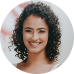 foto de rosto: mulher de cabelo curto, altura do pescoço, cacheado e castanho escuro, sorrindo e olhando para frente.