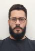 Márcio Medeiros Homem branco cabelo castanho com barba grande e bigode usa óculos e camisa preta